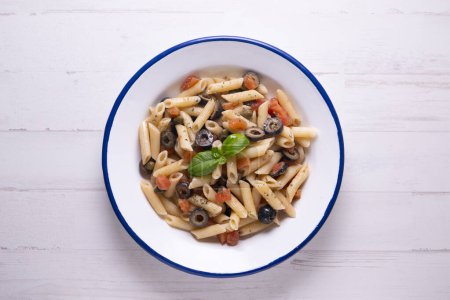 Téléchargez les photos : Recette de pâtes italiennes traditionnelles aux macaronis, olives noires et tomate. - en image libre de droit