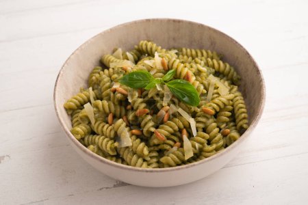 Photo for Pasta with pesto sauce. Pesto is a typical sauce originating from Liguria. Its main ingredient is basil. In addition to the basil, pine nuts and garlic are ground, all seasoned with Parmesan cheese and/or sheep cheese, and olive oil. - Royalty Free Image