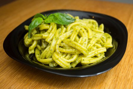 Téléchargez les photos : Pâtes avec sauce pesto. Pesto est une sauce typique originaire de Ligurie. Son ingrédient principal est le basilic. En plus du basilic, les pignons de pin et l'ail sont moulus, tous assaisonnés avec du parmesan et / ou du fromage de brebis, et de l'huile d'olive. - en image libre de droit