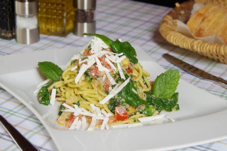 Photo for Noodles with pesto sauce. Pesto is a typical sauce originating from Liguria. Its main ingredient is basil. In addition to the basil, pine nuts and garlic are ground, all seasoned with Parmesan cheese and/or sheep cheese, and olive oil. - Royalty Free Image