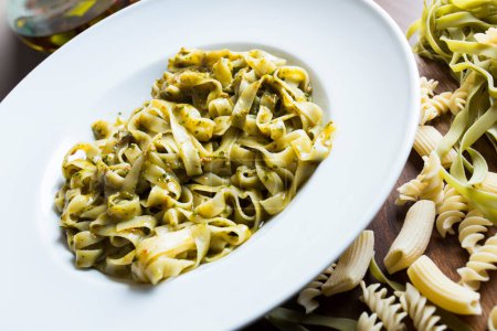 Téléchargez les photos : Nouilles à la sauce pesto. Pesto est une sauce typique originaire de Ligurie. Son ingrédient principal est le basilic. En plus du basilic, les pignons de pin et l'ail sont moulus, tous assaisonnés avec du parmesan et / ou du fromage de brebis, et de l'huile d'olive. - en image libre de droit