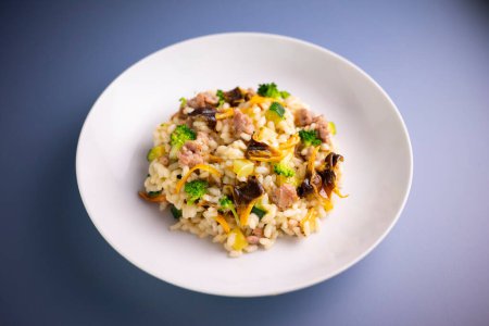 Foto de Receta de risotto italiano con setas y verduras de temporada como calabacín, tomate y queso padano de granna. - Imagen libre de derechos