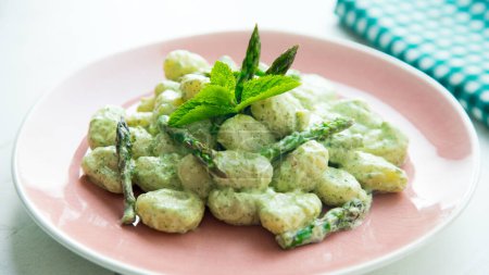 Photo for Gnocchis with yogurt sauce and green asparagus. Gnocchi or gnocchi are a type of Italian pasta. They are made with potatoes, flour and ricotta cheese. - Royalty Free Image