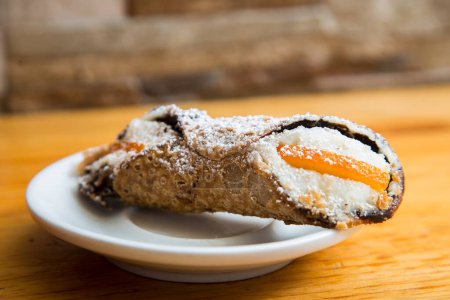 Photo for The cannolo is a typical sweet from the Italian region of Sicily, where it originates from. It consists of a rolled dough in the shape of a tube that contains ingredients mixed with ricotta cheese inside. - Royalty Free Image