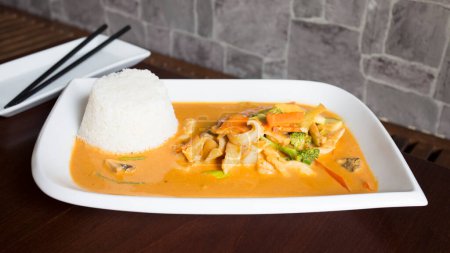Téléchargez les photos : Assiette asiatique combo avec poulet en sauce au curry et légumes servis avec du riz. - en image libre de droit