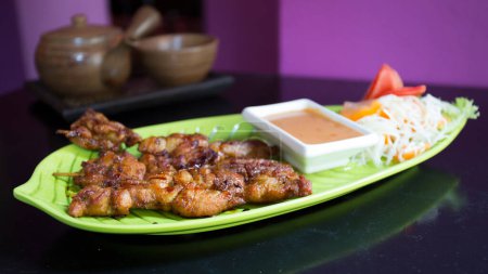 Foto de Brochetas de pollo con salsa de maní. Entrante tradicional en un restaurante tailandés. - Imagen libre de derechos