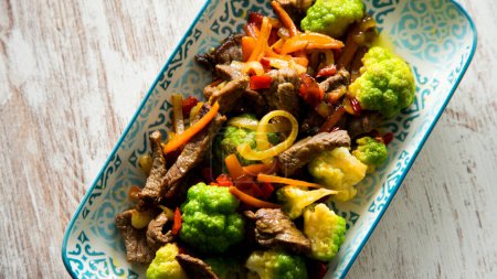 Photo for Beef strips cooked in soy sauce with steamed vegetables such as broccoli and carrots. - Royalty Free Image