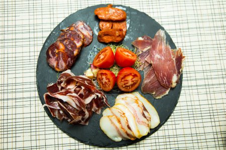 Foto de Tapa con una selección de embutidos y quesos ibéricos de primera calidad como jamón, salchichn y queso Manchego. - Imagen libre de derechos