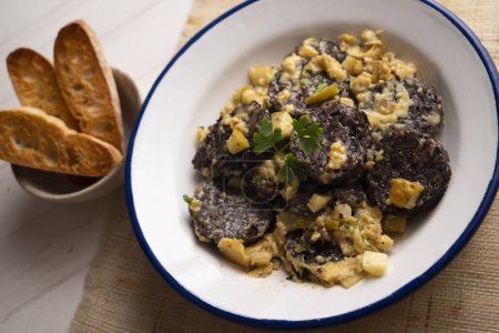 Photo for Scrambled eggs with black pudding. Traditional Spanish tapa. - Royalty Free Image