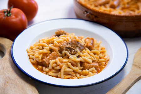 Photo for Baked noodles with pork rib, sausages and tomato. Traditional spanish tapa. - Royalty Free Image
