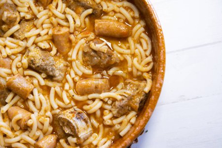 Téléchargez les photos : Nouilles cuites au four avec côtes de porc, saucisses et tomates. Tapa espagnol traditionnel. - en image libre de droit