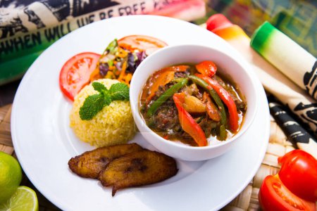 Foto de Verduras a la parrilla servidas con arroz y plátano frito. Plato tradicional jamaicano. - Imagen libre de derechos