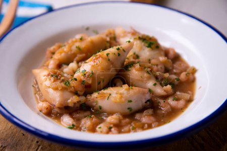 Foto de Tapa tradicional española con calamares cocinados con verduras y salsa de cebolla. - Imagen libre de derechos
