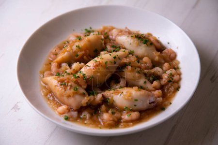 Foto de Tapa tradicional española con calamares también llamados chipirones cocinados con tomate y gambas. - Imagen libre de derechos