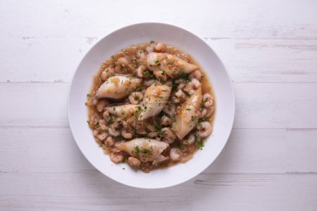 Foto de Tapa tradicional española con calamares también llamados chipirones cocinados con tomate y gambas. - Imagen libre de derechos