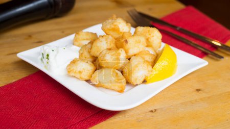 Téléchargez les photos : Choco frito tapa espagnole traditionnelle. Calamar frit et pané avec une tranche de citron. - en image libre de droit