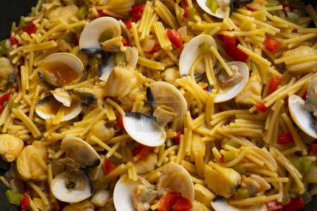 Photo for Traditional Spanish tapa of noodles with monkfish. Cooked in a fideu style paella. - Royalty Free Image