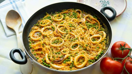 Photo for Traditional Spanish tapa of noodles with calamari. Cooked in a fideu style paella. - Royalty Free Image