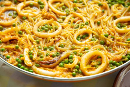 Photo for Traditional Spanish tapa of noodles with calamari. Cooked in a fideu style paella. - Royalty Free Image