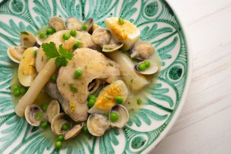 Photo for Basque-style hake with asparagus, hard-boiled egg, clams, peas and green sauce. Traditional Spanish recipe. - Royalty Free Image
