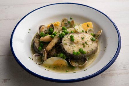 Photo for Basque-style hake with asparagus, hard-boiled egg, clams, peas and green sauce. Traditional Spanish recipe. - Royalty Free Image