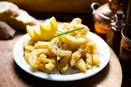 Photo for Fried squid tapa with lemon. Traditional recipe from the north of Spain of squid strips. - Royalty Free Image