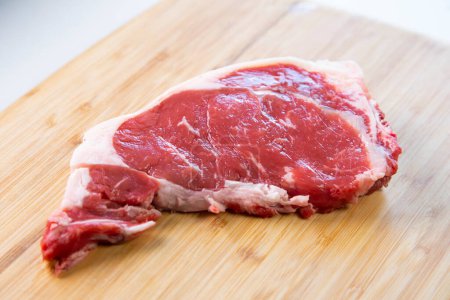 Boeuf steak premium sur base bois sur fond blanc.