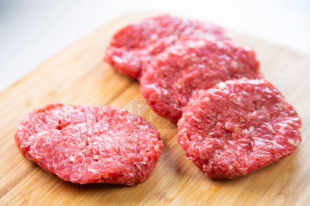 Foto de Carne de hamburguesa Premium sobre base de madera sobre fondo blanco. - Imagen libre de derechos