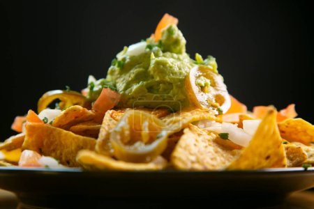 Téléchargez les photos : Nachos au guacamole. Nachos sont un plat d'origine mexicaine, qui consiste à frire des morceaux de tortilla de maïs recouvert d'un fromage spécial. - en image libre de droit