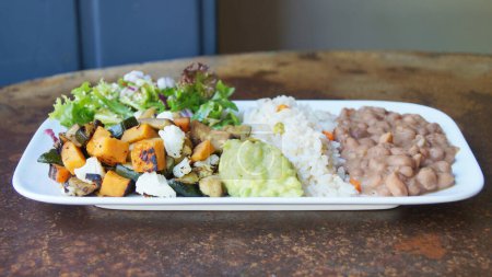 Photo for Mexican combo dish with rice, guacamole, beans and sauted vegetables. - Royalty Free Image