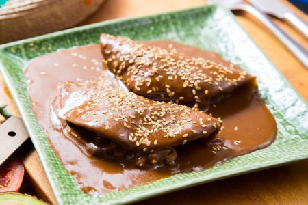 Photo for Mexican tacos covered with mole sauce. The term mole refers to various types of highly seasoned Mexican sauces made primarily from chili peppers and spices. - Royalty Free Image