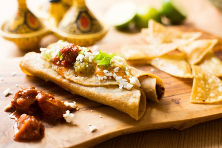 Téléchargez les photos : Flautas est un plat de la gastronomie mexicaine et fait partie de ce que l'on appelle des "snacks mexicains". Le plat se compose de tacos faits de tortillas de maïs roulées et frites ou de tortillas de farine, qui peuvent avoir une teneur différente - en image libre de droit