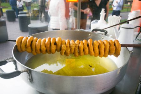 Photo for Picarones are ring-shaped fried sweets made with wheat flour dough mixed with squash, and sometimes sweet potato, bathed in flavored chancaca honey. - Royalty Free Image