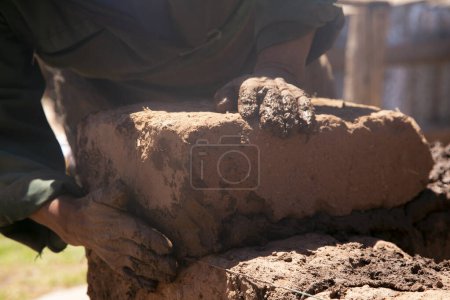Téléchargez les photos : Homme construisant avec ses mains une maison en pisé avec des briques en pisé et de la boue. Région de Llachon du lac Titicaca au Pérou. - en image libre de droit