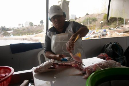 Téléchargez les photos : Lima, Pérou ; 1er janvier 2023 : Femme nettoyant le poisson dans le port de Chorios dans la ville de Lima au Pérou. - en image libre de droit