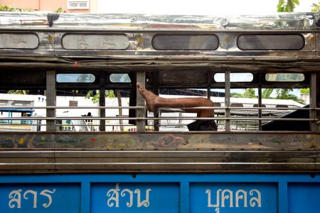 Foto de Un pie sobresaliendo de una ventana de autobús en la ciudad de Bangkok en Tailandia. - Imagen libre de derechos