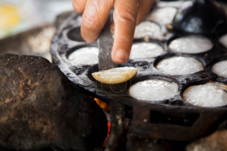 Téléchargez les photos : Femme préparant des desserts thaïlandais à la noix de coco. Kanom krok est un savoureux lait de coco thaïlandais mini crêpes populaire street food ainsi. - en image libre de droit
