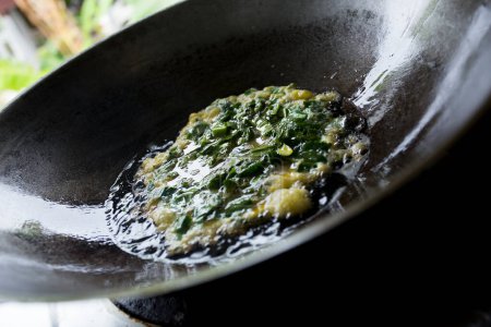 Photo for Spinach omelet cooked in a black frying pan. - Royalty Free Image