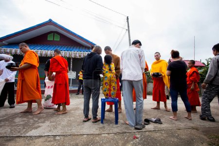 Téléchargez les photos : Chiang Rai, Thaïlande ; 1er janvier 2023 : Famille offrant de la nourriture aux moines bouddhistes dans la ville de Chiang Rai. - en image libre de droit