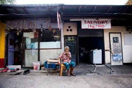 Téléchargez les photos : Bangkok, Thaïlande ; 1er janvier 2023 : Une femme âgée devant une entreprise de blanchisserie à Bangkok. - en image libre de droit