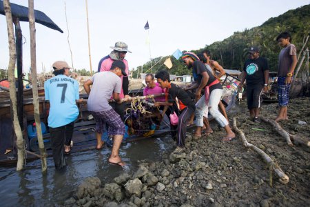Téléchargez les photos : Koh Yao, Thaïlande ; 1er janvier 2023 : Un groupe de pêcheurs thaïlandais chargeant le moteur d'un bateau. - en image libre de droit