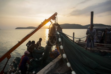 Téléchargez les photos : Koh Yao, Thaïlande ; 1er janvier 2023 : Pêcheurs déchargeant les prises de la journée d'un bateau dans le port de Koh Yao au coucher du soleil. - en image libre de droit