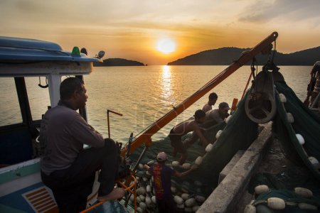 Photo for Koh Yao, Thailand; 1st January 2023: Fishermen unloading the day's catch from a boat in Koh Yao harbor at sunset. - Royalty Free Image