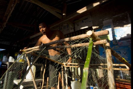 Téléchargez les photos : Koh Yao, Thaïlande ; 1er janvier 2023 : Pêcheur dans le village de pêcheurs de Koh Yao préparant des filets pour pêcher. - en image libre de droit