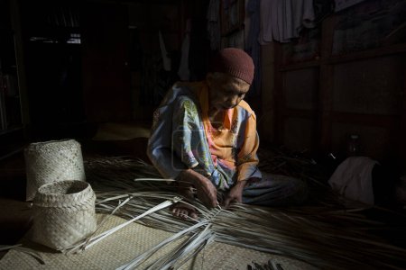 Téléchargez les photos : Koh Yao, Thaïlande ; 1er janvier 2023 : Femme âgée fabriquant un panier avec des feuilles de palmier séchées. - en image libre de droit