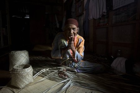 Foto de Koh Yao, Tailandia; 1 de enero de 2023: Mujer mayor haciendo una cesta con hojas de palma secas. - Imagen libre de derechos
