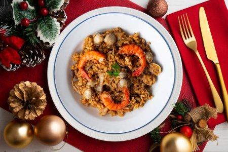 Téléchargez les photos : Paella aux fruits de mer espagnols avec crevettes rouges et palourdes sur une table décorative avec des éléments de Noël. - en image libre de droit