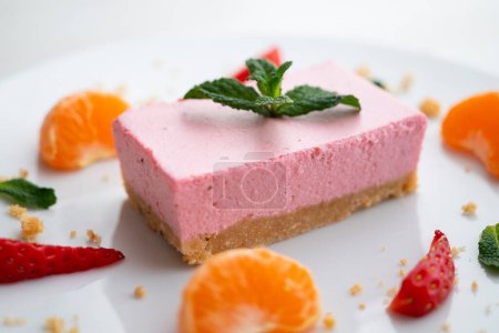 Photo for Portion of strawberry mousse with a cookie base served with fresh fruit and tangerine. - Royalty Free Image