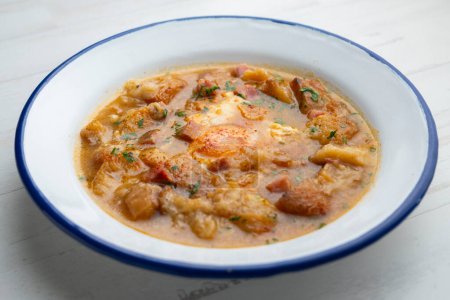 Téléchargez les photos : Soupe castillane aux légumes et morceaux de pain grillé avec un œuf au milieu. - en image libre de droit