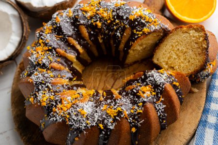 Téléchargez les photos : Gâteau orange et noix de coco fait avec un moule rond et recouvert de chocolat noir. - en image libre de droit
